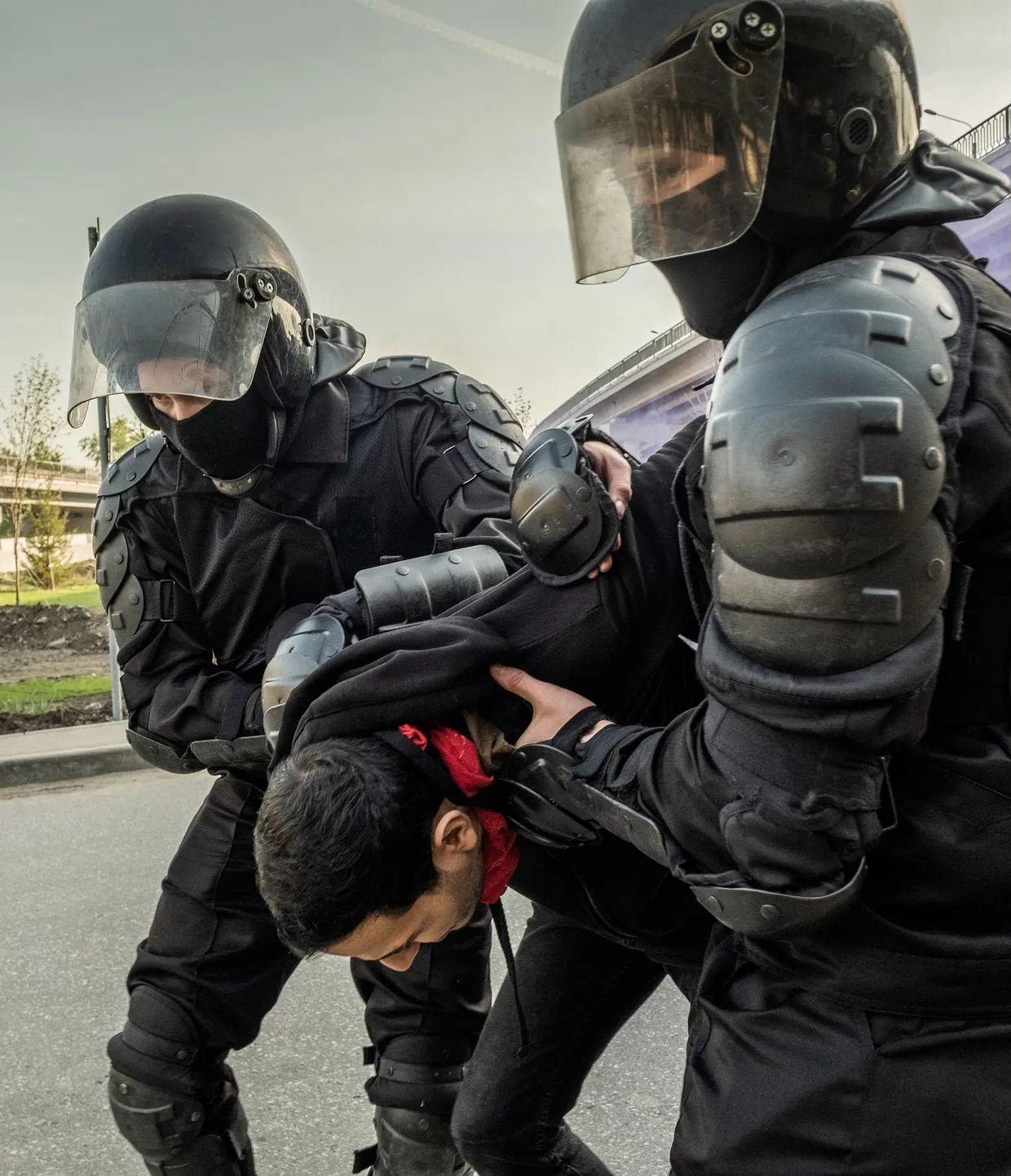 Officers in riot gear restraining a protester